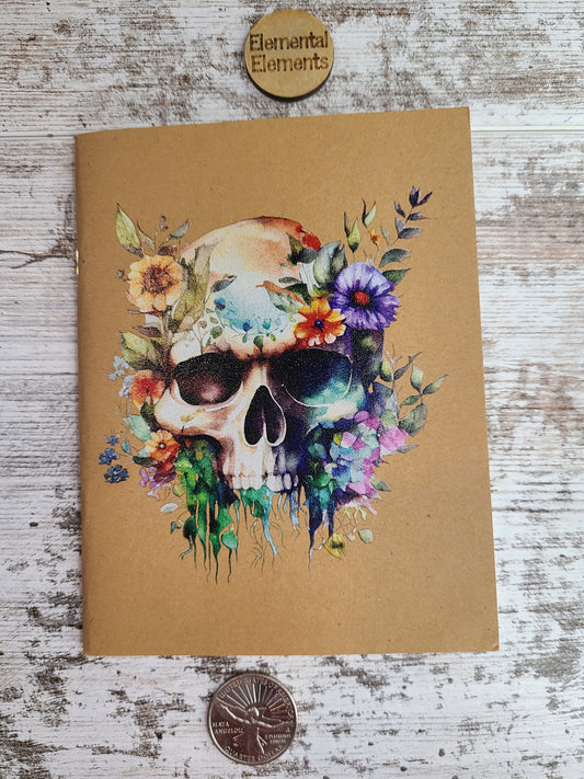 Journal with a colorful watercolor jawless skull and flowers.