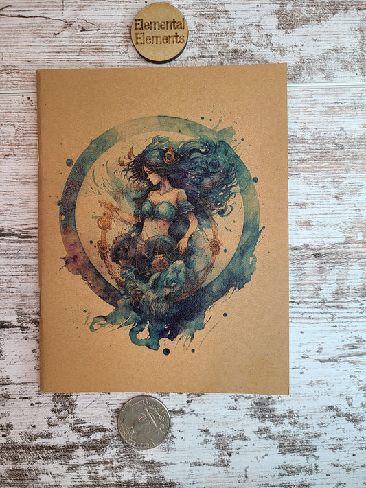 Aquarius zodiac astrology is a human with dark blue and green long flowing hair, blue two-piece clothing, gold accessories in their hair and bottoms. There is a gold detailed u-shaped piece below Aquarius that Aquarius is holding and looking down at, and it is all within a watercolor circle made up of blues, greens, and purple.