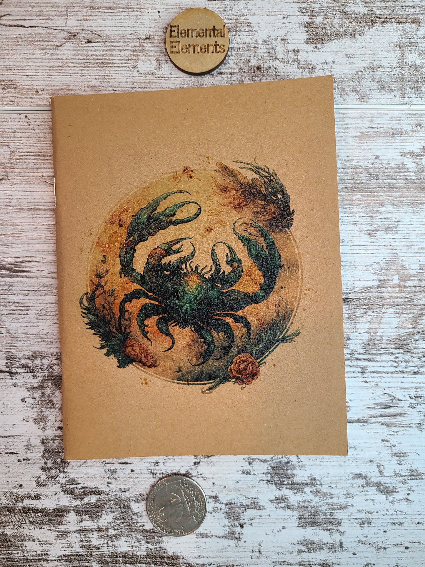 Cancer zodiac astrology journal shows a water color depiction of a large blue and brown crab within a brown, tan, and blue circle that has reef and floral elements surround.