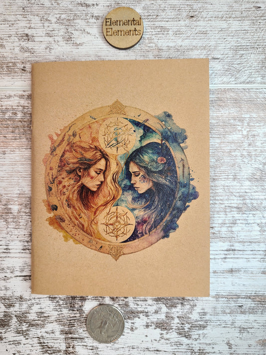Gemini journal two humans with long hair facing each other. The left person is red and orange. The right person is blue and green. They both have flowing long hair surrounded by a circle with associated colors peeking out like clouds on each side.