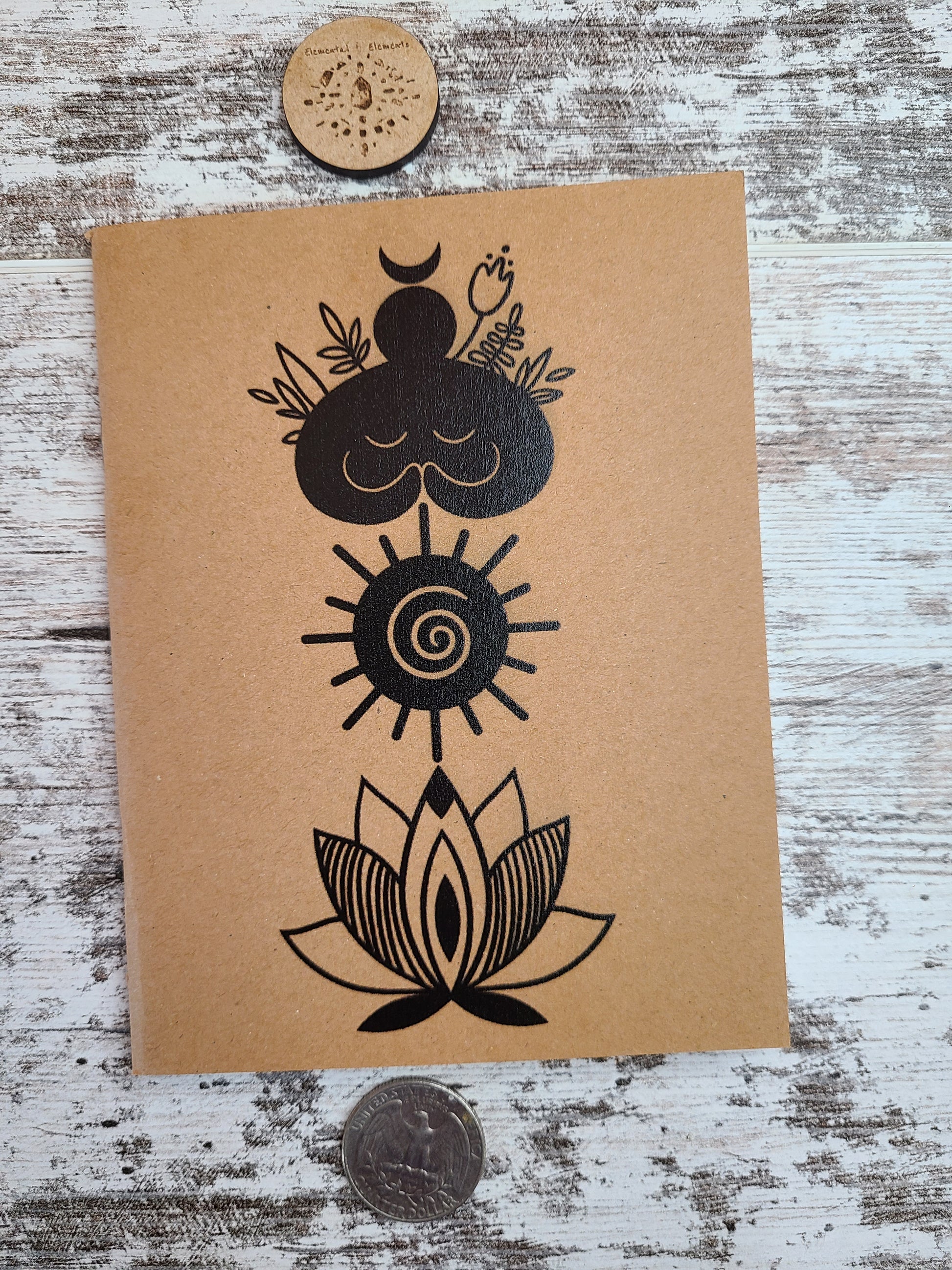 Elemental Elements journal notebook with a goddess figure, spiral sun, and lotus flower vertically top to bottom.