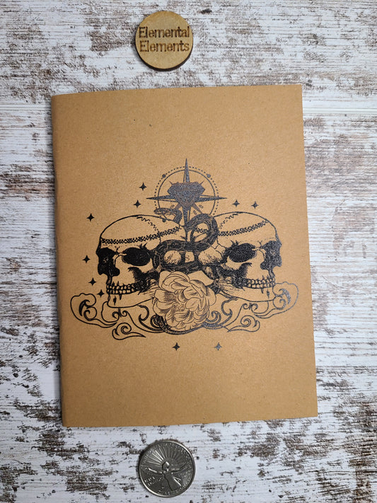 Journal with 2 skulls and a snake, rose and compass in the middle.