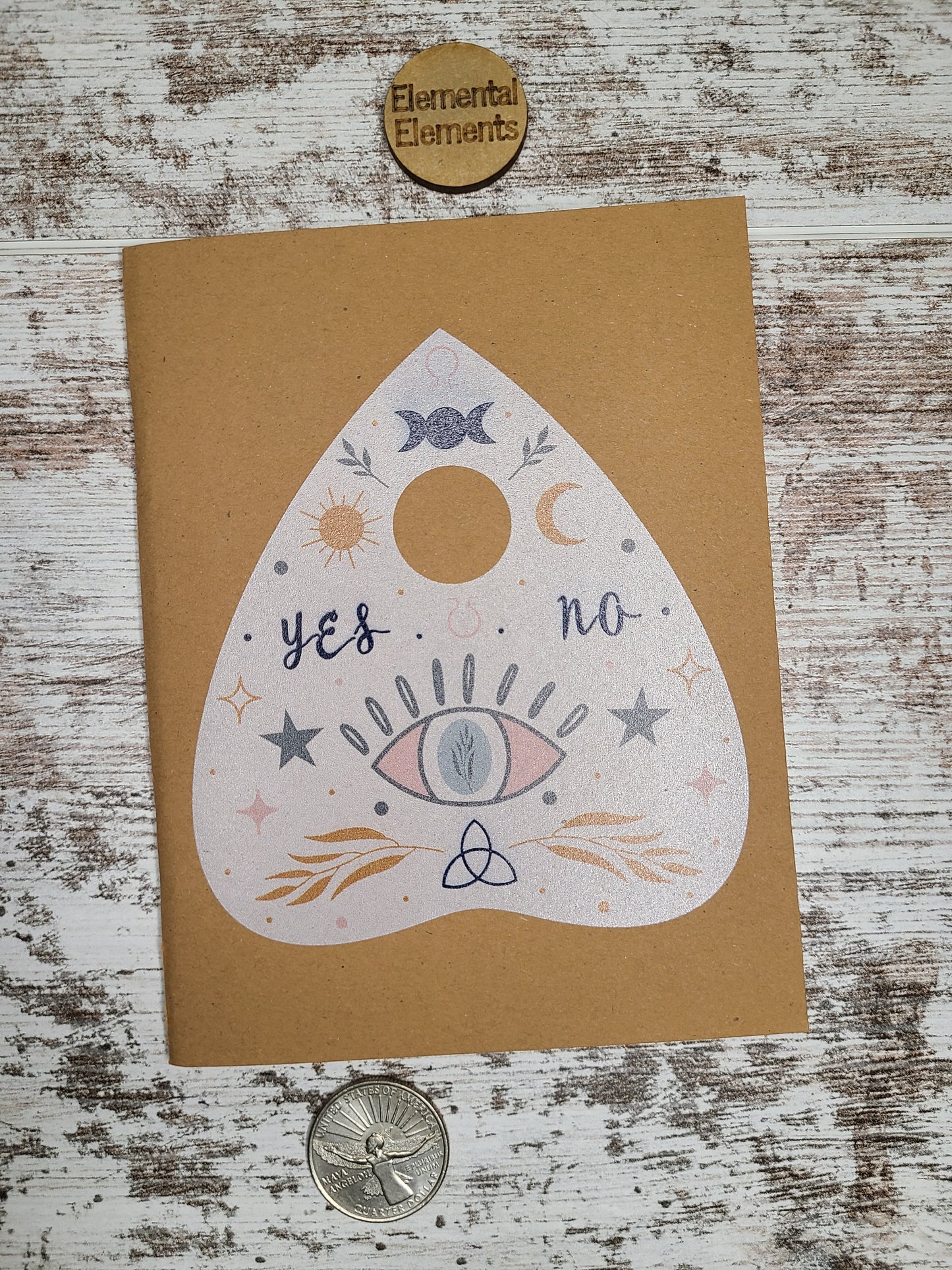 Planchette journal with triple moon goddess, the moon and sun, an evil eye, stars, and leaves. 