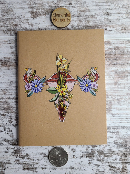 Journal with a uterus that has floral elements on both fallopian tubes and in the center of the uterus.