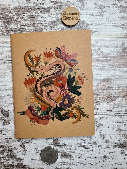 Pink Snake with Black underbelly surrounded by  many flowers and leaves, two crescent moons, and two moths in shades of blue, pink, purple, green, orange, and yellow.