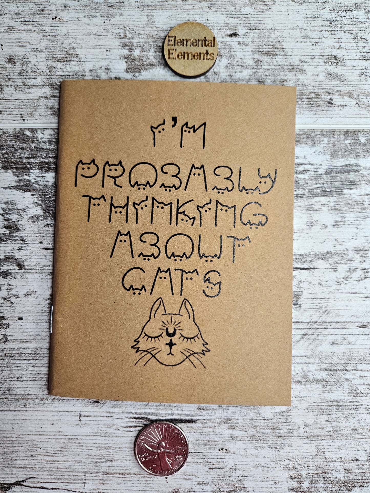 Journal with I'm probably thinking about cats in black cat shaped text with a cute black cat head that has closed eyes, a crescent moon on its forehead, and a star shaped nose.