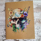 Journal with a colorful watercolor jawless skull and flowers.