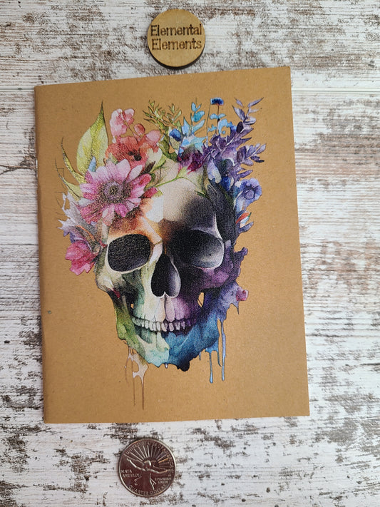 kraft paper journal with a watercolor rainbow skull and flowers.