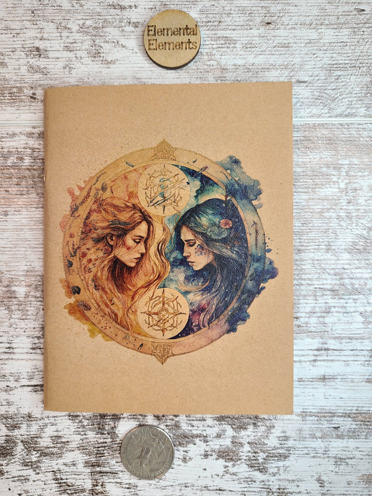 Gemini journal two humans with long hair facing each other. The left person is red and orange. The right person is blue and green. They both have flowing long hair surrounded by a circle with associated colors peeking out like clouds on each side. 